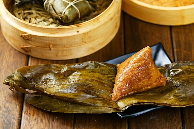 Rice dumplings zongzi and bamboo steamer on wooden table