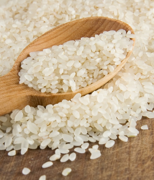 Rice grain in wooden spoon on table