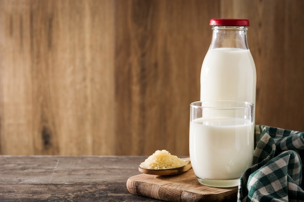 Rice milk in glass and bottle on wooden table. 