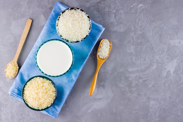 Rice milk and rice seeds on a gray background Rice milk in glass on a blue napkin