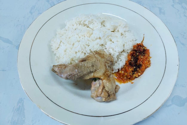 rice mixed with fried fish and tempeh vegetables on a white plate on the table