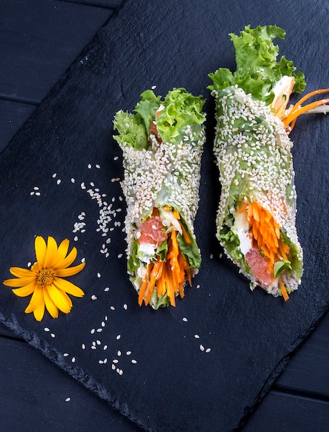 Rice paper rolls with sesame vegetables and tuna Asian dish On a dark stone Healthy food