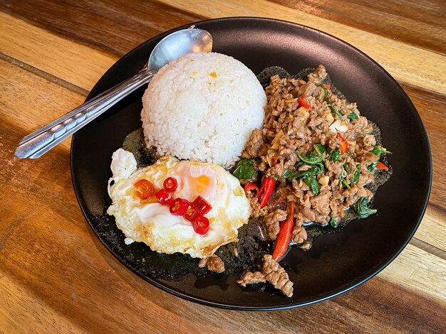 Rice topped with stir-fried beef and basil with fried egg on the table