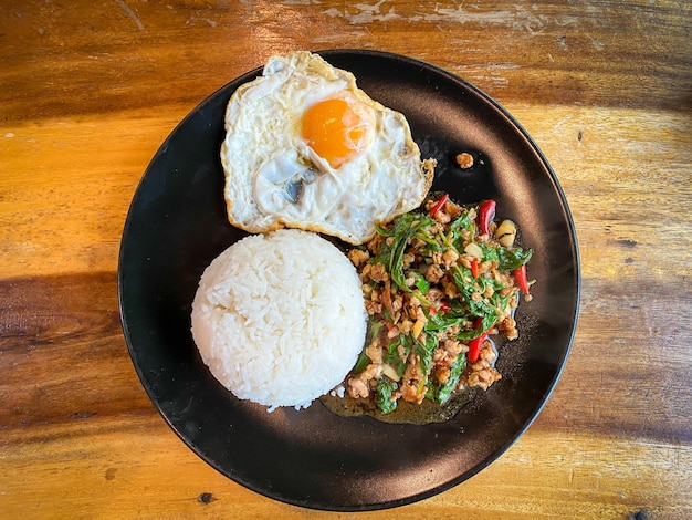 Rice topped with stir-fried pork and basil with a fried egg on the table