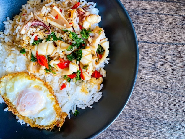 Rice topped with stirfried squid and basil with fried egg