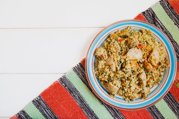 rice with chicken on a plate on a bright striped mat