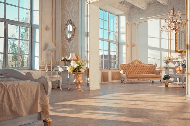 Rich apartment interior with golden baroque decorations on the walls and luxury furniture. the room is flooded with the rays of the setting sun