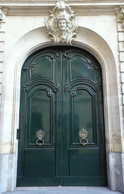 The rich decor decorates an entrance door of the old building of traditional architecture of in downtown Paris