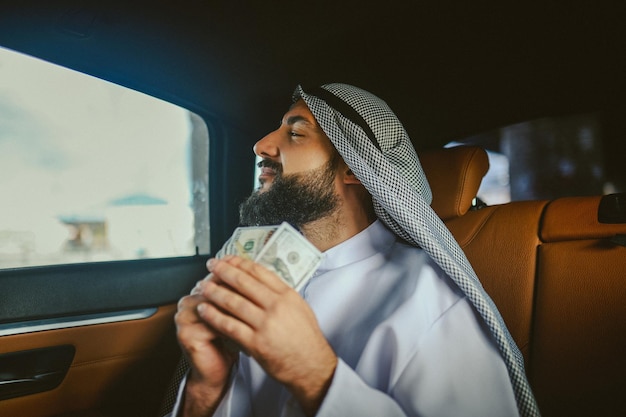 Rich man in a car Saudi man in a traditional clothing in a car holding money