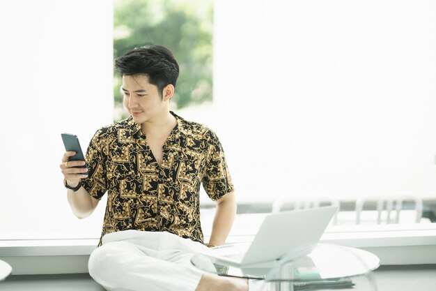 Rich man using mobile phone and working with laptop at the cafe