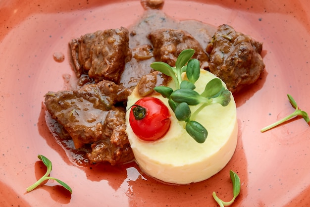 Rich and savory beef bourguignon with mashed potatoes on a plate on wooden surface