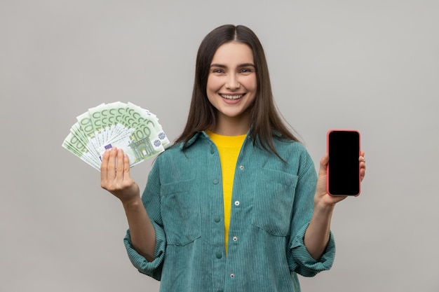 Rich woman holding euro banknotes and phone with blank screen for advertisement or promotion