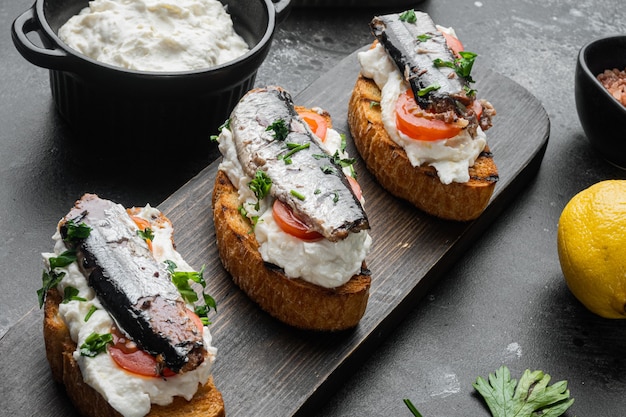 Ricotta sardine toast set, on black dark stone table background