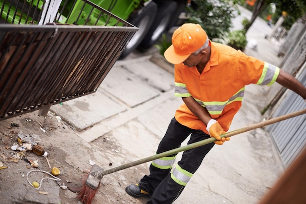 Ridding the streets of rubbish Cropped shot of a garbage collection worker sweeping the sidewalk