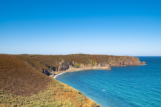 Ride on the GR34 in Brittany with far off Cape Frehel and its lighthouse