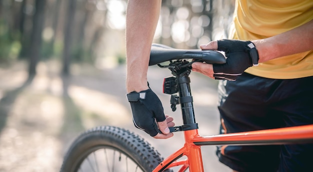 Rider adjusting seat height on bicycle standing in sunny forest