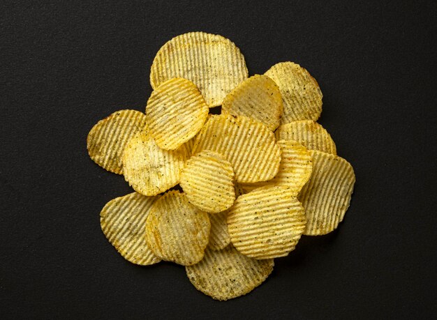 Photo ridged potato chips on black background top view