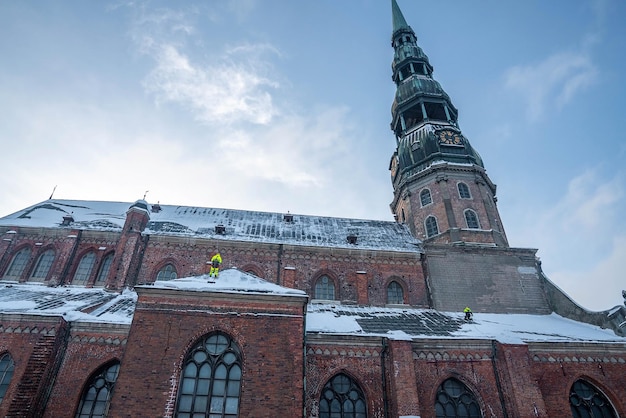 Riga, Latvia. January 10, 2021. Workers cleaning off snow from the roof of the St. Peters cathedral in Riga, Latvia.