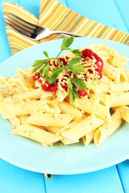 Rigatoni pasta dish with tomato sauce on blue wooden table close up