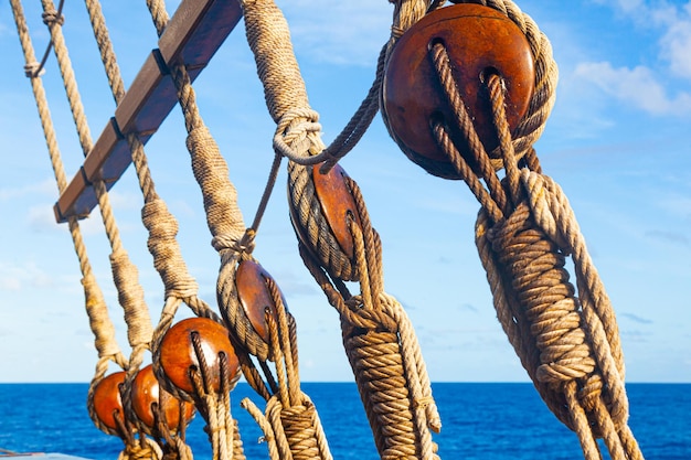 Rigging old wooden ship against the background of sea and sky with rope ladder pulleys and ropes