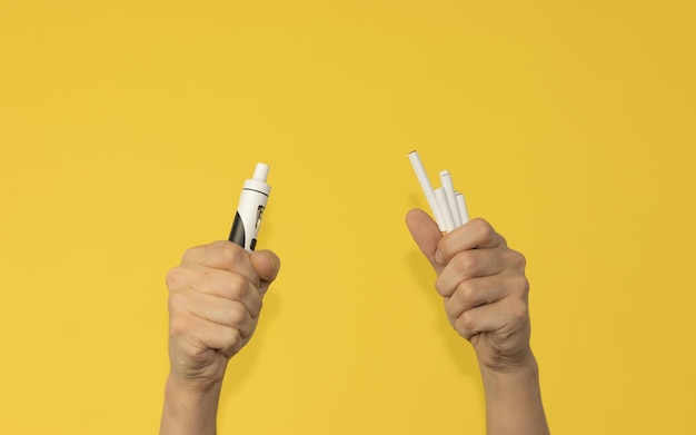 Right hand with vaper and left hand with cigars on yellow background