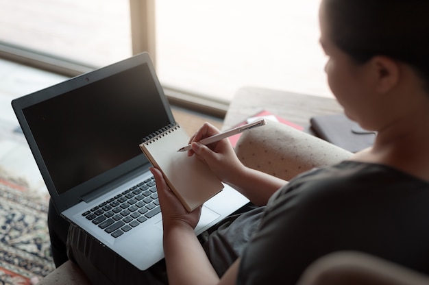 Right-handed woman writing on small notepad