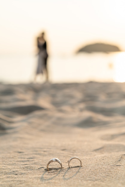 rings on beach with bride and groom