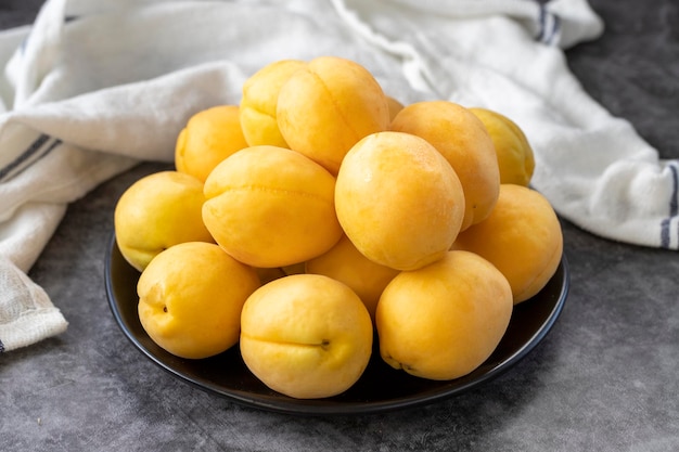 Ripe apricots on a dark background Fresh and juicy apricots on the plate Organic food close up