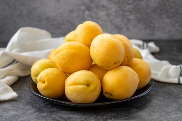 Ripe apricots on a dark background Fresh and juicy apricots on the plate Organic food close up