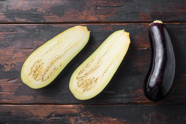 Ripe aubergine or eggplant half sliced on old wooden background top view.