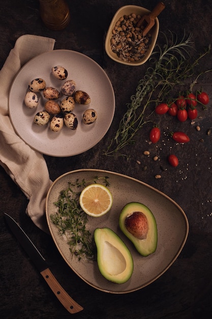 Ripe avacado decoreted on the plate and raw Quail eggs on the dark tableHealthy breakfast vegetable food