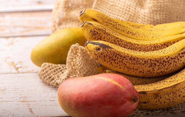 Ripe bananas and mangoes details of a bunch of very ripe bananas and some mangoes selective focus