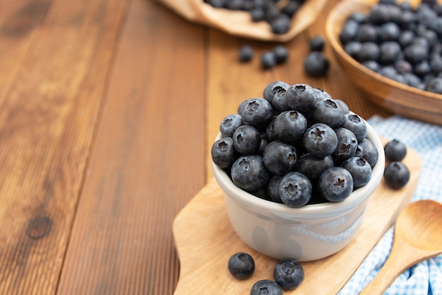 Ripe blueberries in the bowl on the wooden table, Fresh berries for breakfast, Copy space.