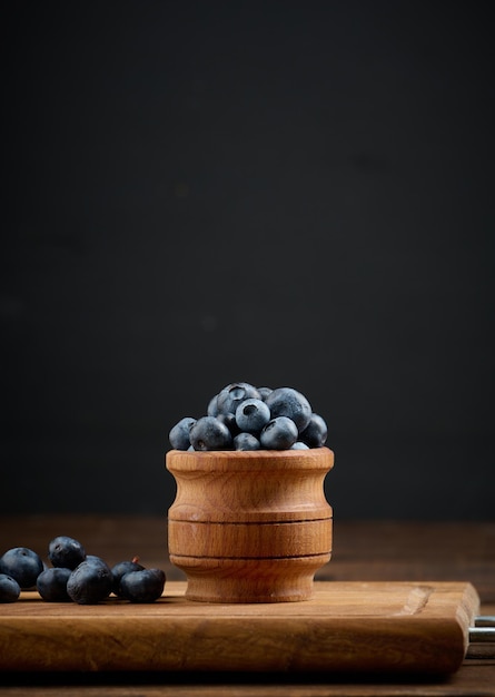 Ripe blueberries in a wooden bowl on the table black background