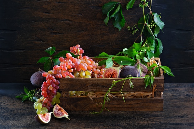 Ripe bunch of red and green grapes and white wine in an decanter on old wooden boards