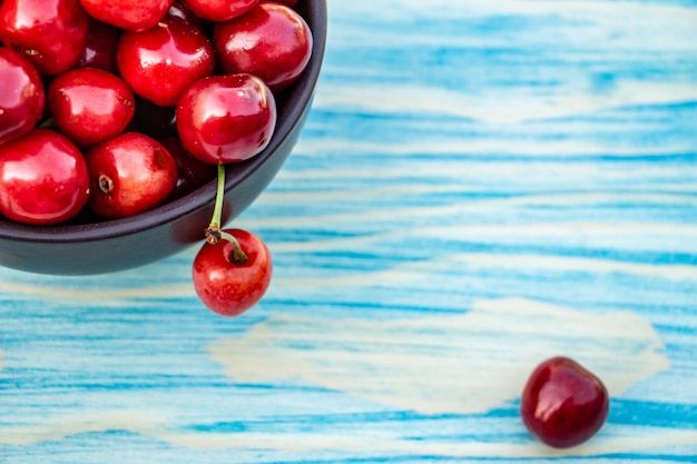 Ripe cherries on blue wooden background copy space