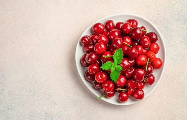 Ripe cherries in a plate on a pink background with space to copy. Top view.