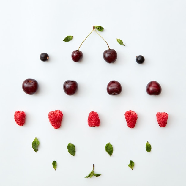 Ripe cherries and raspberries,currants with mint leaves on a white background. Creative food pattern