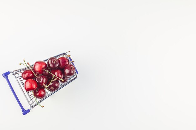 Photo ripe cherries in a shopping cart isolated