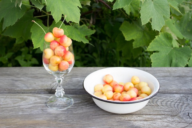 Ripe cherries Yellow and red sweet cherries in glassware and wooden table summer concept Early harvest sweet cherry