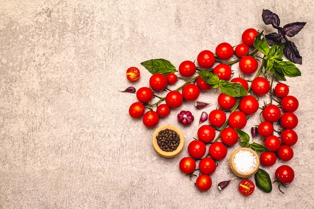 Ripe cherry tomatoes and spices on a stone background