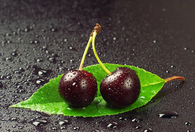 Ripe cherry with water drops and green leaf