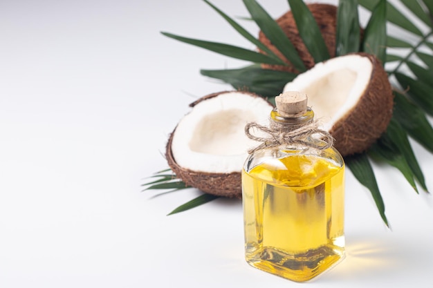 Ripe coconut with coconut oil a white background with leaves.