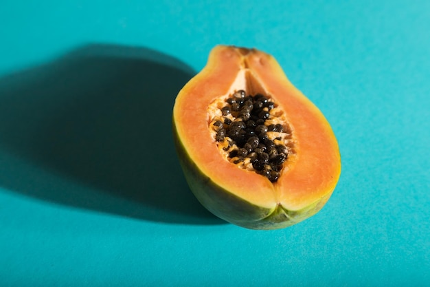 Ripe cut papaya on blue pastel background Side view close up hard light