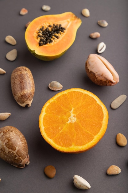 Ripe cut papaya and orange on gray pastel background Side view close up