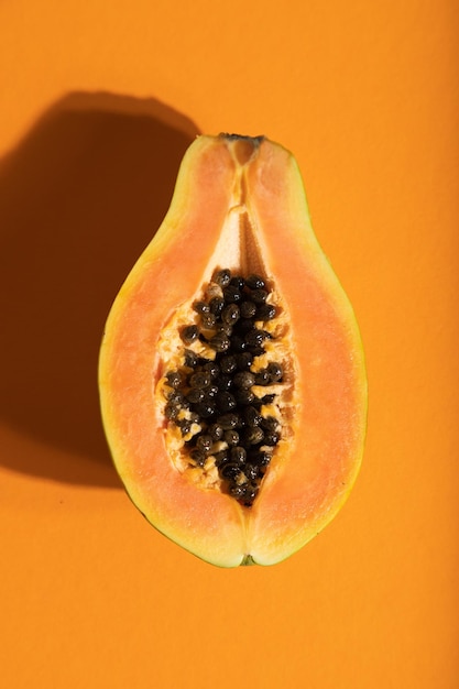 Ripe cut papaya on orange pastel background Top view close up hard light