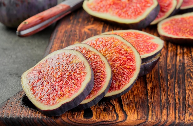 Ripe figs cut into slices on a wooden cutting board closeup selective focus seasonal ripe fruits mediterranean diet idea for background