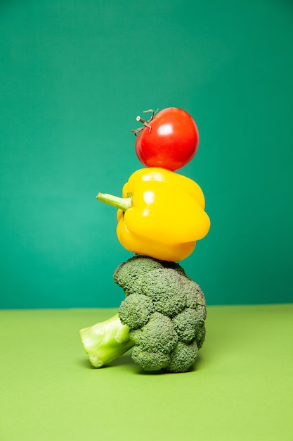 Ripe fresh colorful broccoli bell pepper and tomato against green background