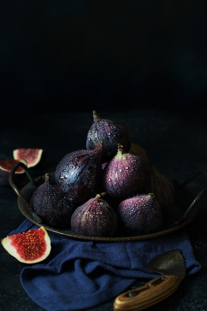 Ripe fresh figs in a tin cup on a dark background, vertical orientation, southern fruit