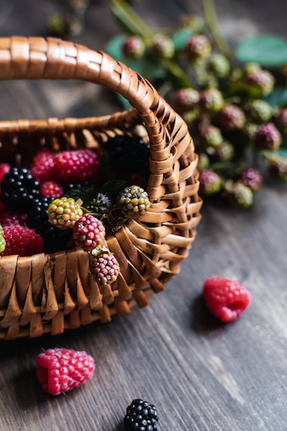 Ripe fresh raspberries and blackberries with straw basket